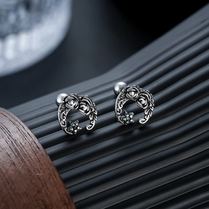 Macro shot of vintage titanium steel moon and rose earrings with green star gems