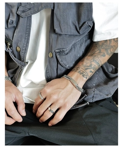 Detail of silver double-layered chain bracelet and minimalist wide rings on a model