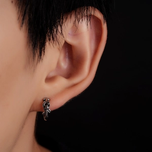 Macro side view of vintage titanium steel rose stud earring on earlobe with dark backdrop