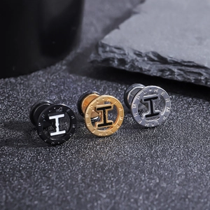 Détail macro de boucles d'oreilles en acier titane tricolore avec motif lettre H évidé