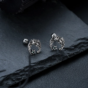 Vintage titanium steel moon and rose stud earrings with green zircon on rock surface