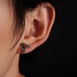 Gothic ear stud featuring a red heart stone held by a skeleton hand with bat wings
