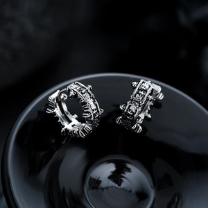 Detail of vintage silver titanium earrings with gothic cross relief and punk textures