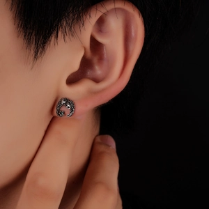 Macro detail of vintage titanium steel earring with intricate vine texture and green zircon