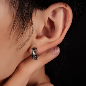 Close-up of a silver titanium steel stud earring with gothic embossed relief textures