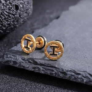 Gros plan sur des boucles d'oreilles en titane doré avec logo H noir sur pierre