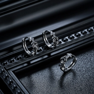 Close-up of retro titanium steel rose and cross earrings with black gemstone inlays