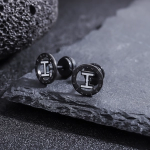 Vue macro de boucles d'oreilles en acier noir mat avec logo H et marque gravée