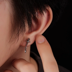 Detailed close-up of a vintage titanium sword earring with sparkling rhinestones on ear