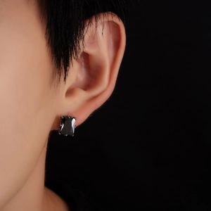 Gros plan d'un clou d'oreille rectangulaire en zircon noir avec une base en métal texturé
