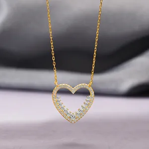 Elegant gold heart pendant necklace with shimmering crystals on grey silk backdrop