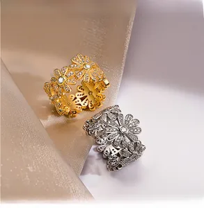 Close-up of silver and gold daisy rings with 5A cubic zirconia on silk fabric