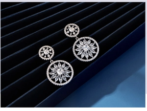Detail showing S925 silver sunflower earrings with sparkling cubic zirconia on blue velvet