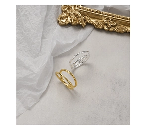 Close-up of stacked triple-layer silver and gold rings on minimalist marble background
