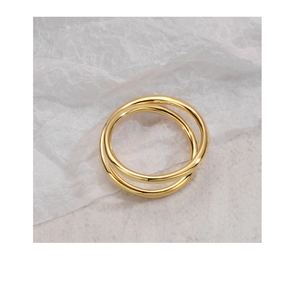Top view of minimalist double-layered crossover gold ring on marble background