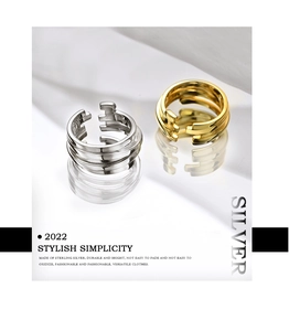 Macro shot of layered gold and silver S925 sterling silver rings on white reflective surface