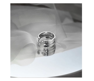 Macro view of a minimalist silver S925 multi-layered adjustable geometric ring on mirror