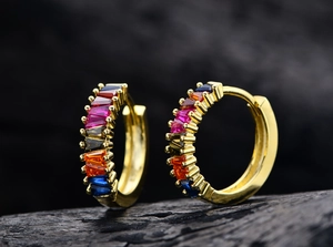 Macro shot of gold earrings featuring rainbow gradient baguette-cut colorful zircons