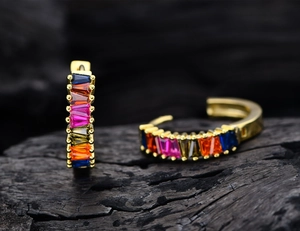Macro shot of gold hoop earrings with multi-color baguette-cut zircons in claw setting