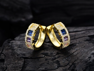 Macro view of 925 sterling silver stamp on gold hoop earrings with multi-color gems