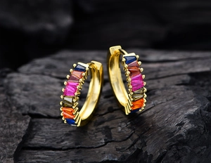 Macro detail of gold hoop earrings set with baguette-cut rainbow cubic zirconia stones