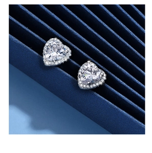Vue macro des boucles d'oreilles halo en forme de cœur argenté avec diamants brillants