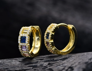 Macro detail of gold-plated silver hoop earrings with multicolored square-cut gems