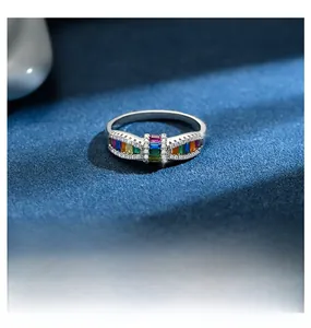 Macro shot of silver bow ring with vibrant rainbow zircon inlay on deep blue background