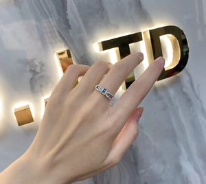 Macro shot of silver rainbow ring featuring multi-colored rectangular gemstones on a finger