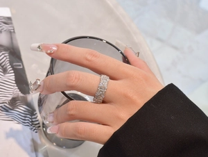 Close-up of sparkling floral cubic zirconia silver ring on hand with elegant marble background