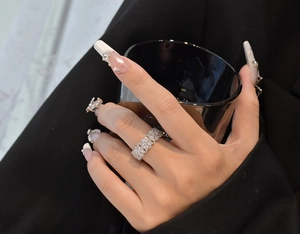 Gros plan d'une bague double rangée en cristaux marquise portée sur un fond sombre