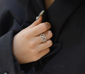 Détail d'une bague trèfle ajourée en argent S925 sertie de pierres blanches sur main
