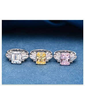 Macro detail of three rectangle-cut crystal rings on blue satin with vibrant sparkle