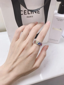 Close-up of a silver ring featuring rainbow-colored baguette gemstones and round diamonds