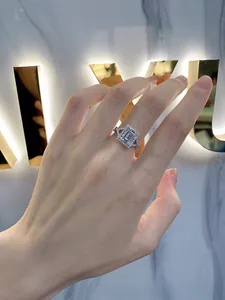 Detail of emerald cut halo ring with twisted pavé shank worn on finger
