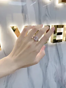 Close-up of emerald-cut halo engagement ring in s925 silver worn on a finger
