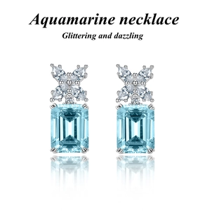 Detailed close-up of emerald-cut aquamarine earrings with marquise zircon butterfly motif