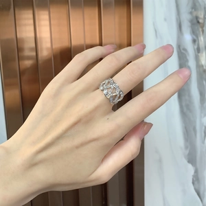 Gros plan de la bague ajourée large sertie de diamants baguette et motif croisé