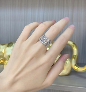 Gros plan d'une bague large argentée ondulée sertie de diamants sur la main d'un mannequin