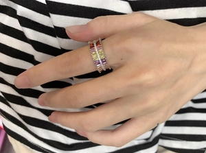 Close-up of rainbow baguette cut stones set in a silver eternity band on a hand