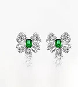 Detail of silver bow earrings with emerald green gemstone and sparkling white stones