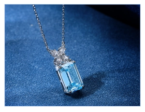 Detailed macro view of an emerald-cut aquamarine pendant with marquise leaf accents