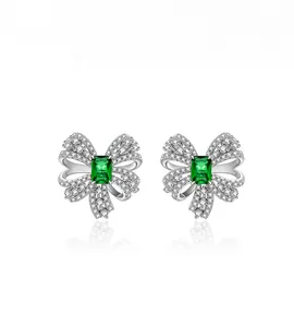 Detail of emerald cut green gemstone earrings with a sparkling bow setting and diamonds