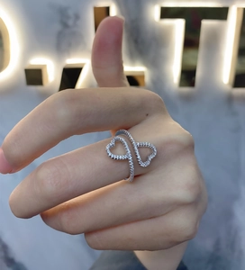 Close-up of interlocking silver double heart ring with zircon inlay on female hand
