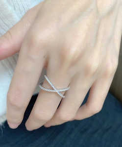 Close-up of a s925 sterling silver criss-cross ring with pavé cubic zirconia on finger