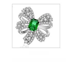 Detailed macro view of silver bow-knot earring with rectangular emerald gemstone inlay
