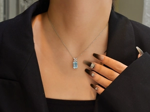Close-up of aquamarine pendant necklace with X-shape diamond accents on model