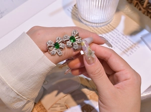 Macro detail of silver bow earrings with emerald green stone and zircon pavé inlay