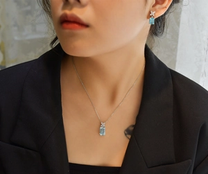 Macro shot of 8x12 aquamarine necklace and earrings set worn with black blazer