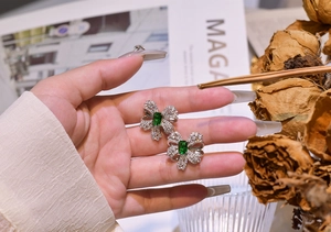 Detailed close-up of emerald bow earrings with silver plating and white zircon inlay